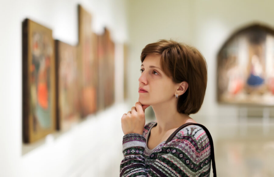 Mujer observando atentamente una obra de arte durante una visita guiada en un museo.